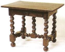 Table avec pieds torses et tiroirs avec une poignée tombante.
